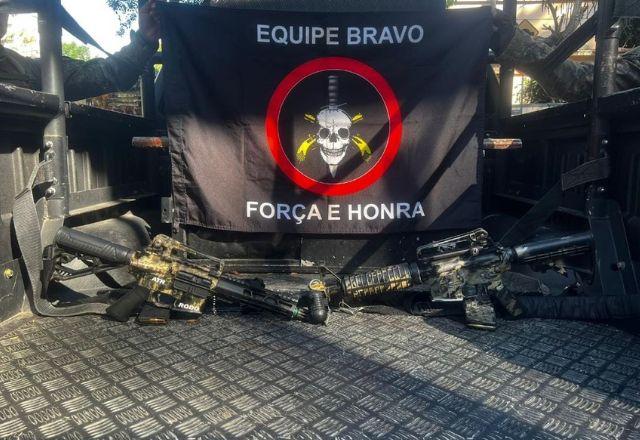 fuzis apreendidos à frente de uma bandeira do BOPE