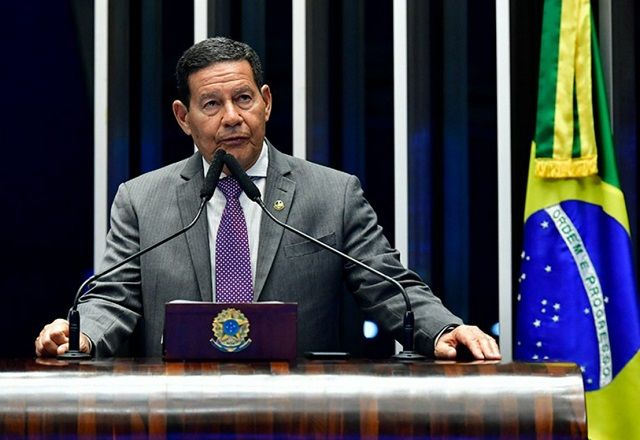 Hamilton Mourão fala ao microfone, próximo a bandeira do Brasil | Waldemir Barreto/Agência Senado