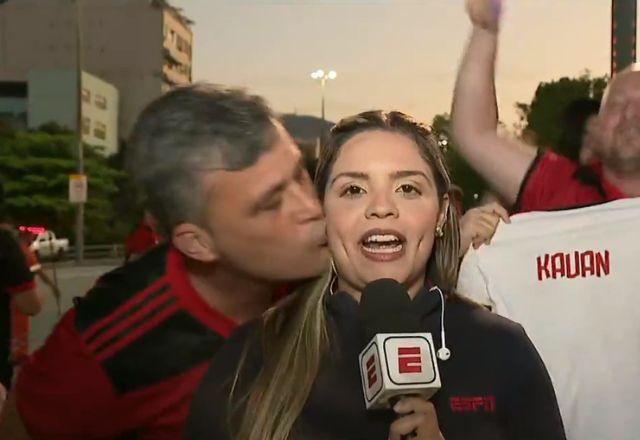 homem, com camisa do flamengo, beija o rosto de repórter que fazia entrada ao vivo