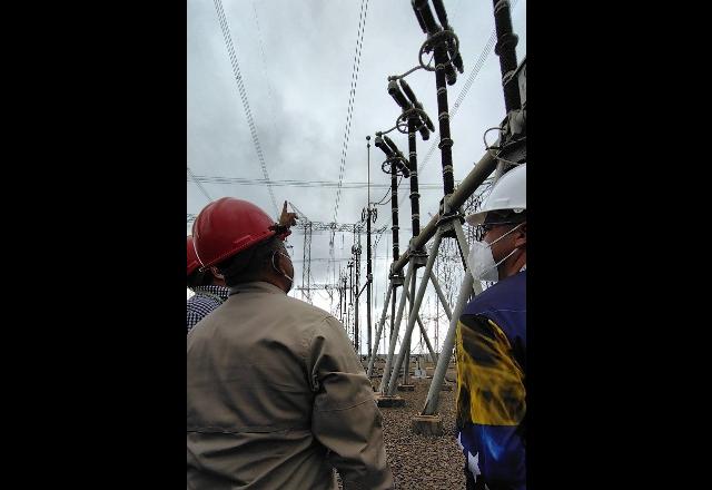 imagem de homens de capacete olhando para torres de energia na Venezuela
