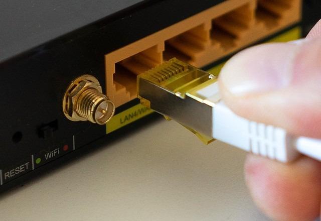 imagem de uma pessoa com um cabo conectando o roteador de wifi