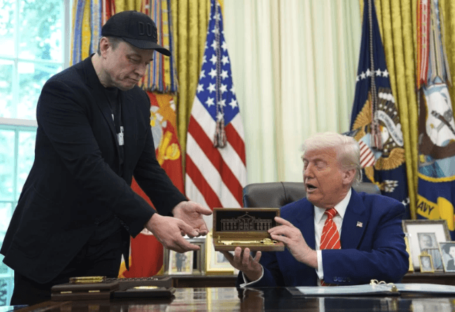 O presidente Donald Trump, à direita, entrega uma chave a Elon Musk durante uma coletiva de imprensa | Foto: AP/Evan Vucci