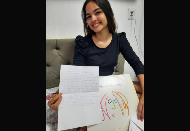 jovem sentada com uma carta na mão, escrita à caneta azul pelo pai que morre vítima da covid em 2021
