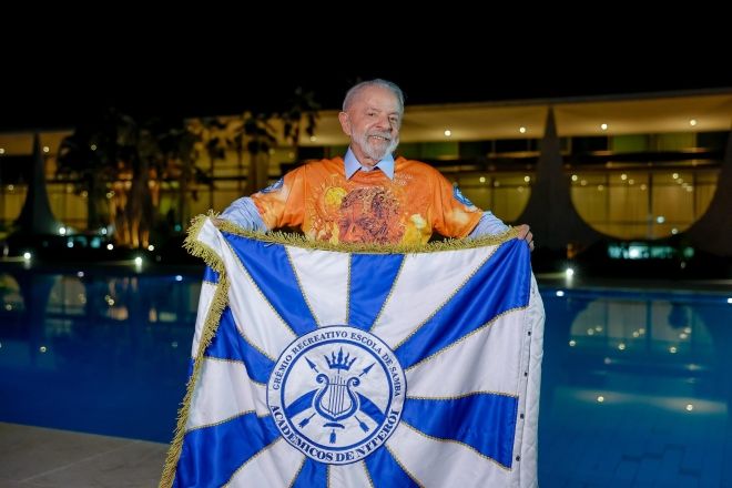Lula segurando a bandeira do Acadêmicos de Niterói, escola de samba que fará homenagem ao presidente durante desfile no Carnaval de 2026 | Ricardo Stuckert/PR