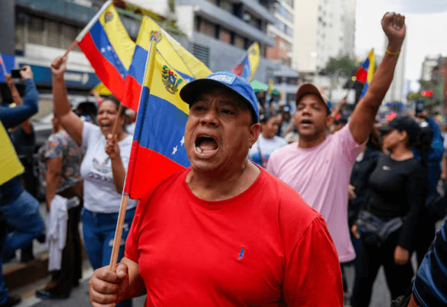 Pessoas participam de uma marcha pedindo a libertação do presidente da Venezuela, Nicolás Maduro, após ele e sua esposa, Cilia Flores, terem sido capturados em decorrência de ataques dos EUA à Venezuela | Reprodução/Reuters