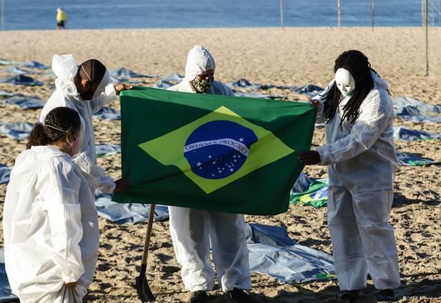 manifestantes com a bandeira do brasil, vestidos de branco, na praia de copacabana em protesto pelas 400 mil mortes da covid 19