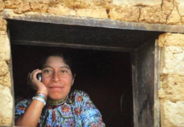 mulher zona rural ao celular na janela de casa