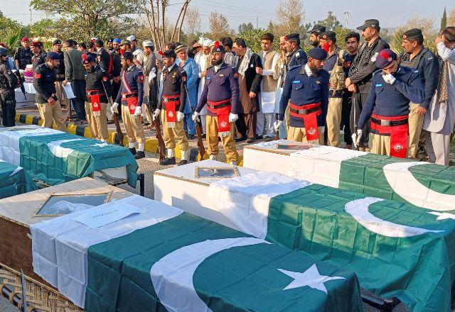 Policiais e moradores se reúnem ao lado dos caixões cobertos com a bandeira do Paquistão dos policiais mortos em ataque terrorista contra uma viatura, durante um funeral em Kohat | REUTERS/Syed Basit
