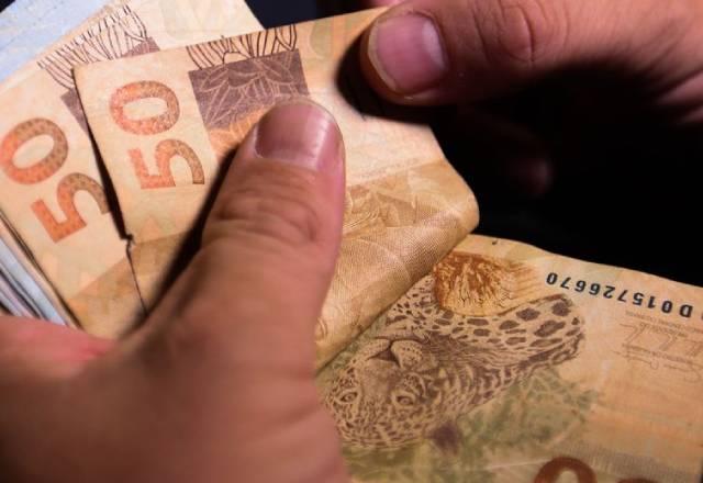 pessoa contando notas de 50 reais
