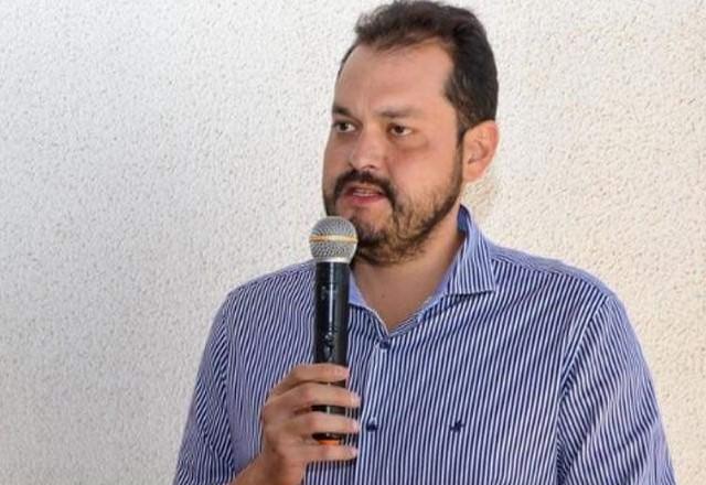 prefeito com camisa listrada segurando um microfone na mão enquanto fala