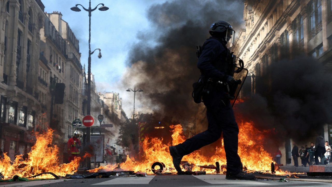 Polícia de choque francesa passa por objetos em chamas em meio a confrontos com manifestantes em Paris | REUTERS/Abdul Saboor
