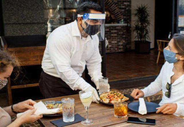 restaurante com garçon e clientes de máscara