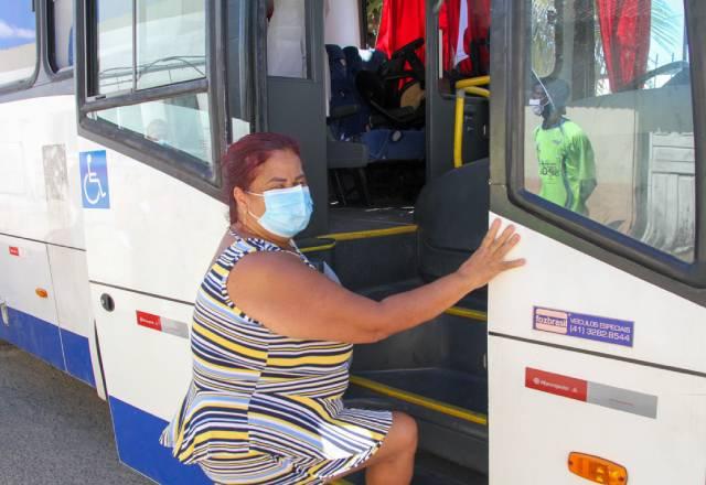 senhora de máscara subindo em ônibus