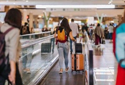 Pessoa carregando mala em aeroporto | Reprodução