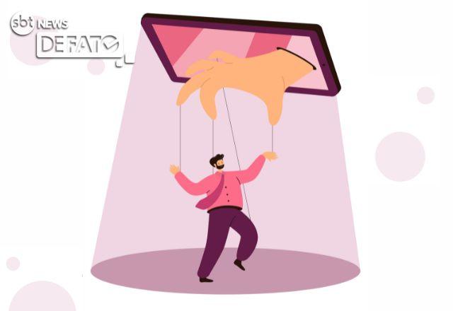 uma mao saindo do celular manipulando uma pessoa com traje de terno e gravata