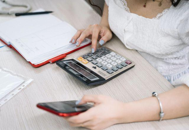 uma mulher fazendo calculos em uma calculadora