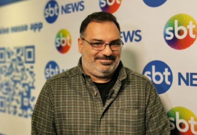 yan boechat é um jornalista. a imagem mostra um homem branco com barba rala, que veste uma camisa xadrez escura