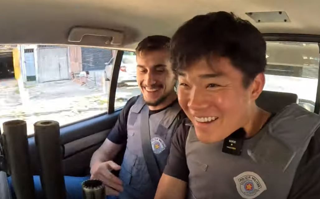 Policiais militares de São Paulo deixaram o youtuber posar com uma arma e participar de uma perseguição policial no banco de trás de uma viatura | YouTube / Reprodução
